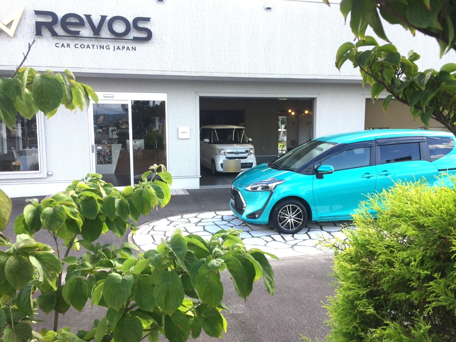 RevoS店舗前 木々の緑ごしに佇むシエンタ