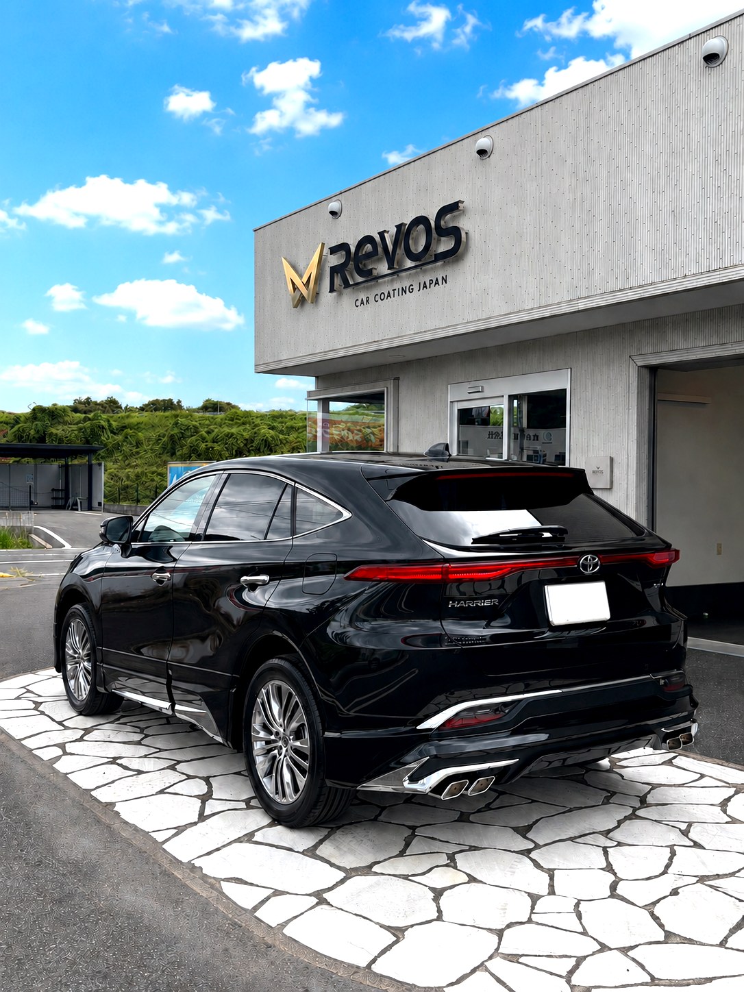 RevoSの看板の前、青空の下に停まる黒のトヨタ ハリアーの後ろ姿