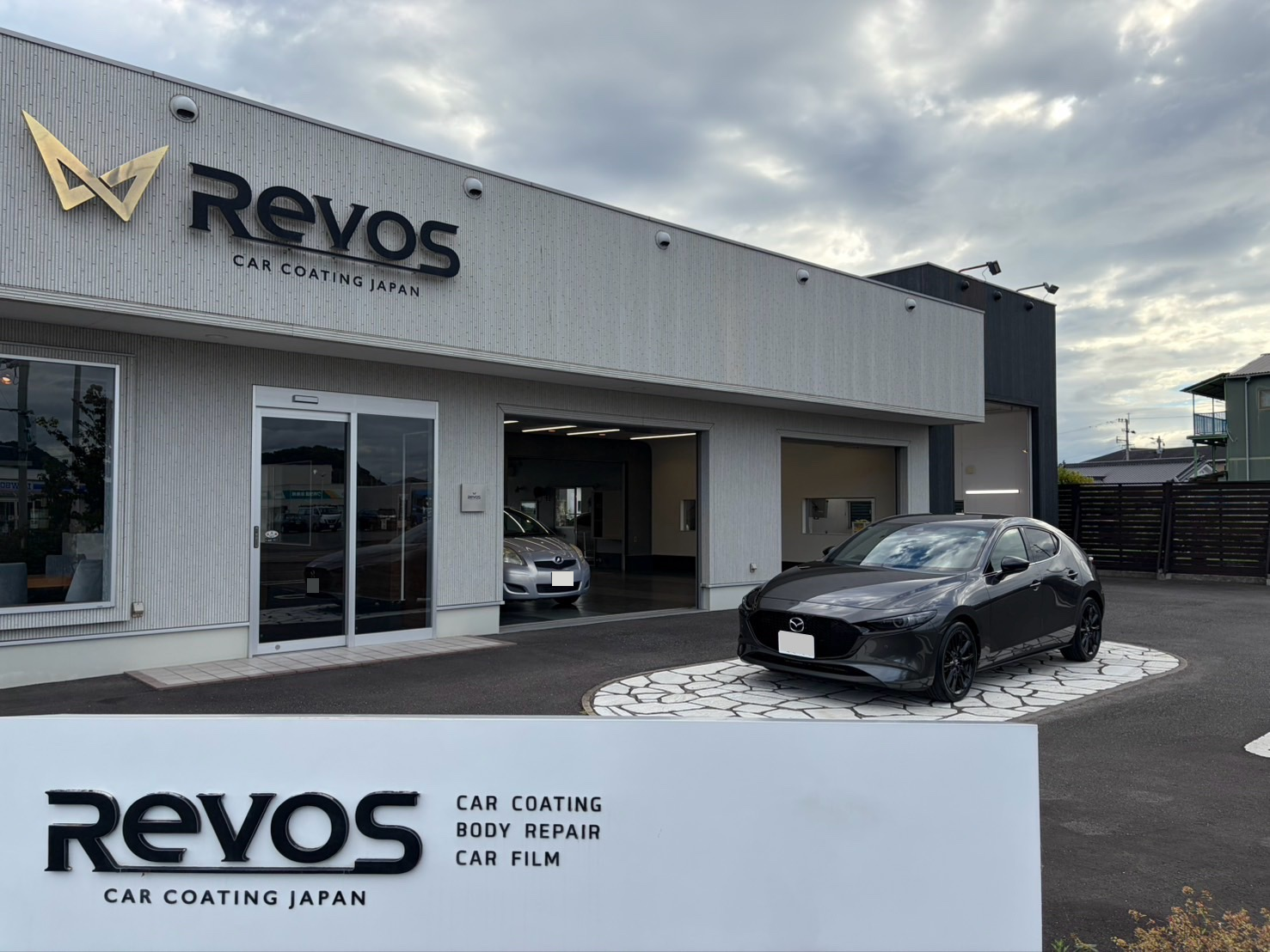 RevoSの店舗と看板の前に停まる施術後のマツダ3