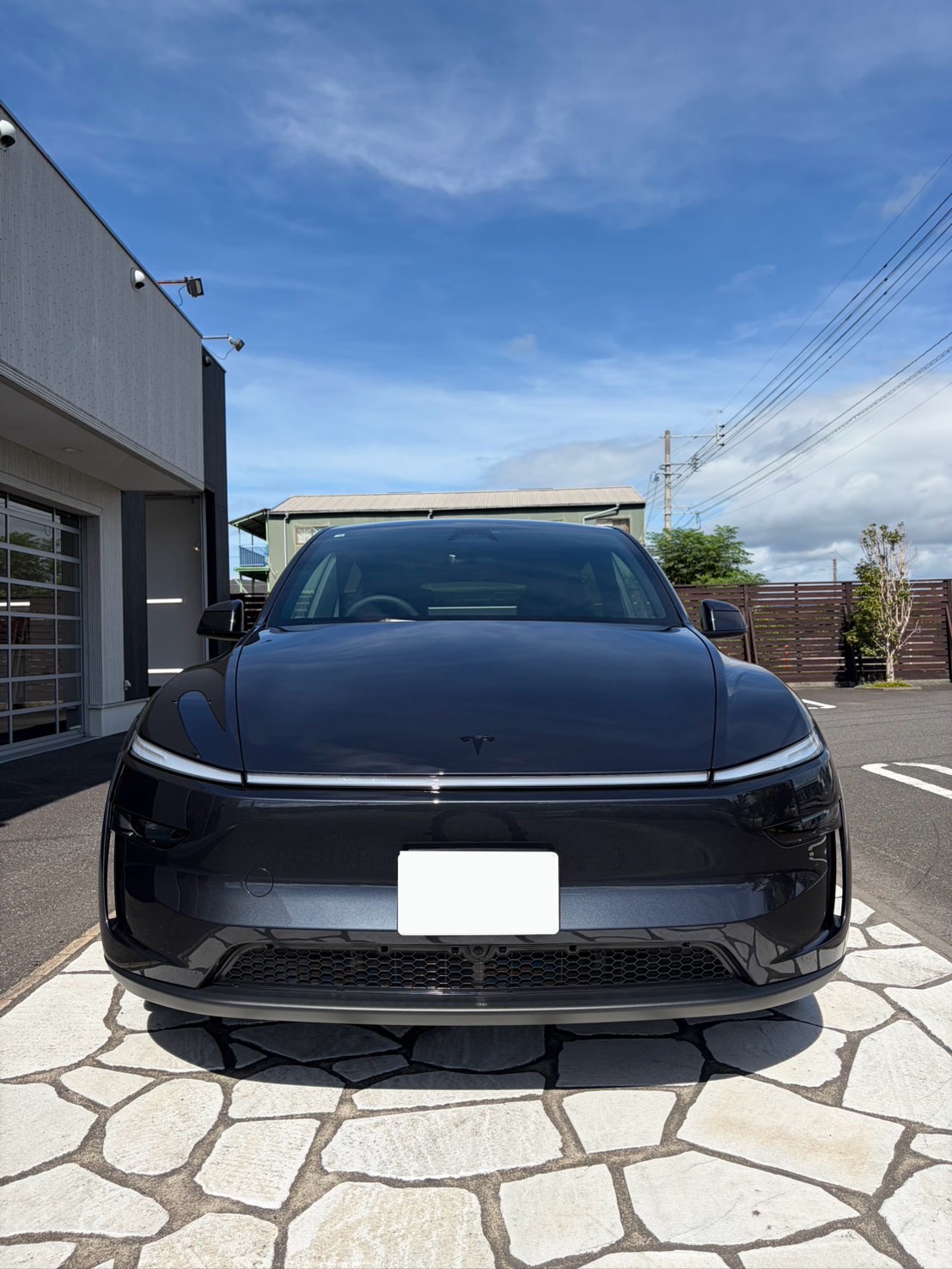 屋外で仕上がりを確認するグレーメタリックのテスラ モデルYの正面