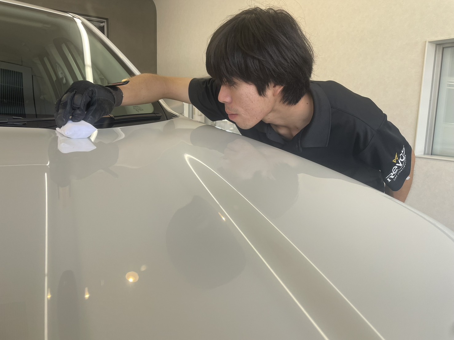 塗装面を見ながらコーティングを塗り込むスタッフ