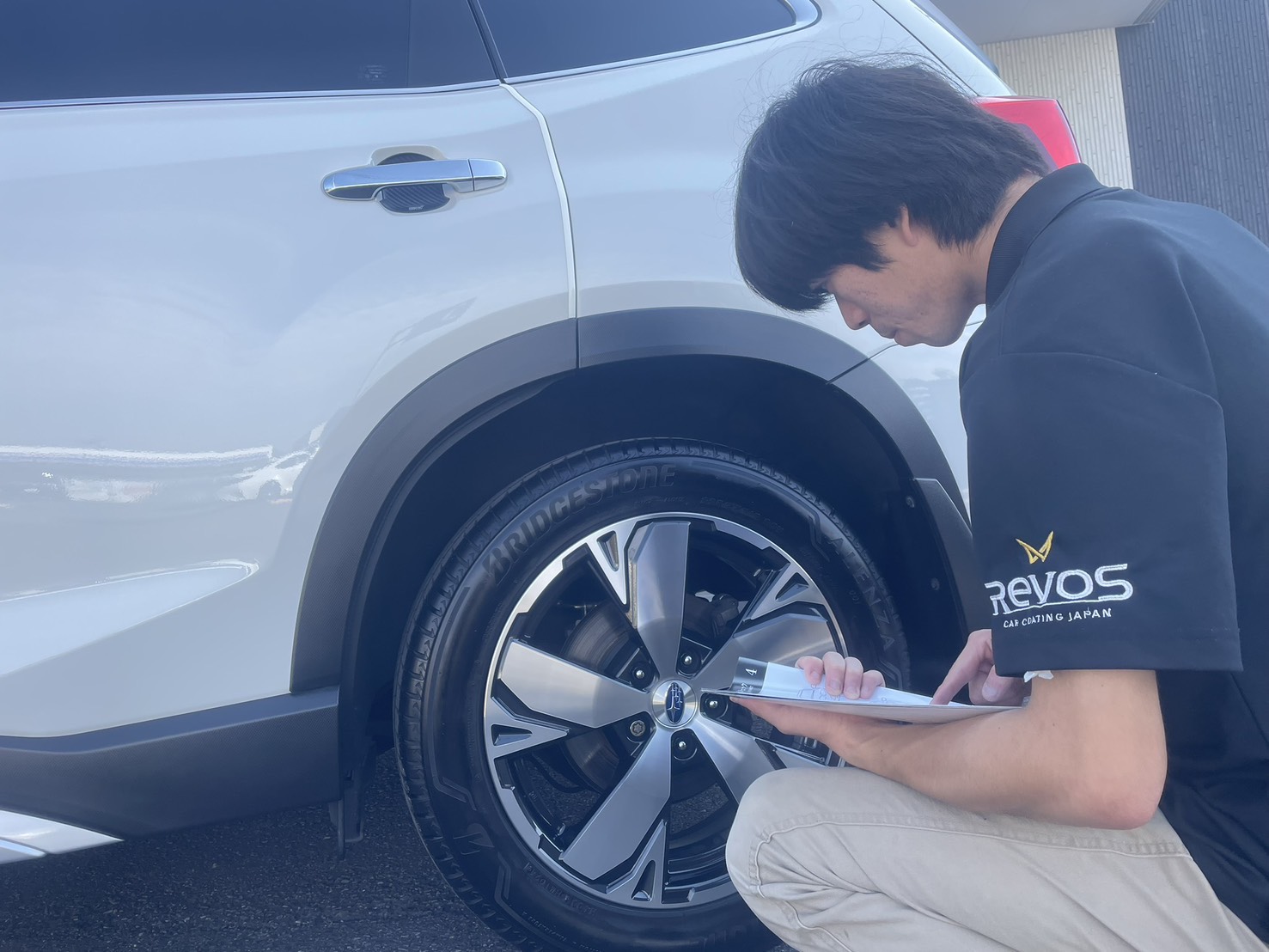 屋外でホイール周辺を確認するスタッフ