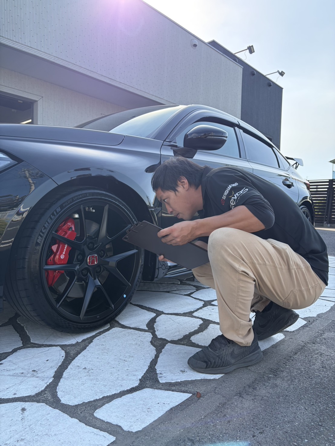 屋外でホイール周りを確認するスタッフ