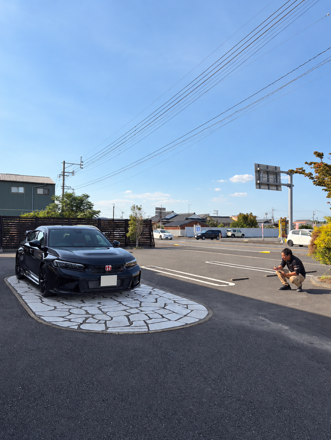 屋外で車から離れて全体を確認するスタッフ